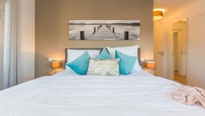A hotel room with a large bed, a painting of a pier, and two bedside lamps. - Exclusive vacation apartment in Zingst: 132 m² of comfort right on the Baltic Sea beach - (Zingst)