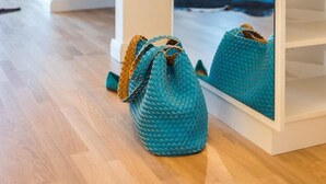 A room with a white wardrobe, a mirror reflecting a purple chair and a blue rug, and a teal woven bag on the floor. - Exclusive vacation apartment in Zingst: 132 m² of comfort right on the Baltic Sea beach - (Zingst)