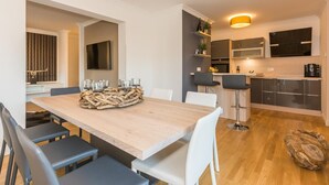 A modern kitchen with dark cabinets, a wooden dining table, and a bar area. - Exclusive vacation apartment in Zingst: 132 m² of comfort right on the Baltic Sea beach - (Zingst)
