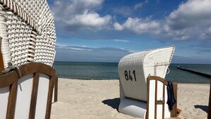 Una silla de playa con el número '841', un banco de madera y vista al océano.