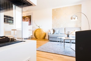 A modern living room with a grey sofa, a round wooden coffee table, and a floor lamp. - Modern lodging house apartment "Strandmuschel" directly on the Baltic Sea beach Zingst - (Zingst)