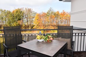 Un balcon avec une table et des chaises, un panier de fruits et un bouquet de fleurs.