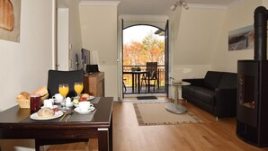 Una sala de estar moderna con comedor, chimenea y un balcón con follaje otoñal.