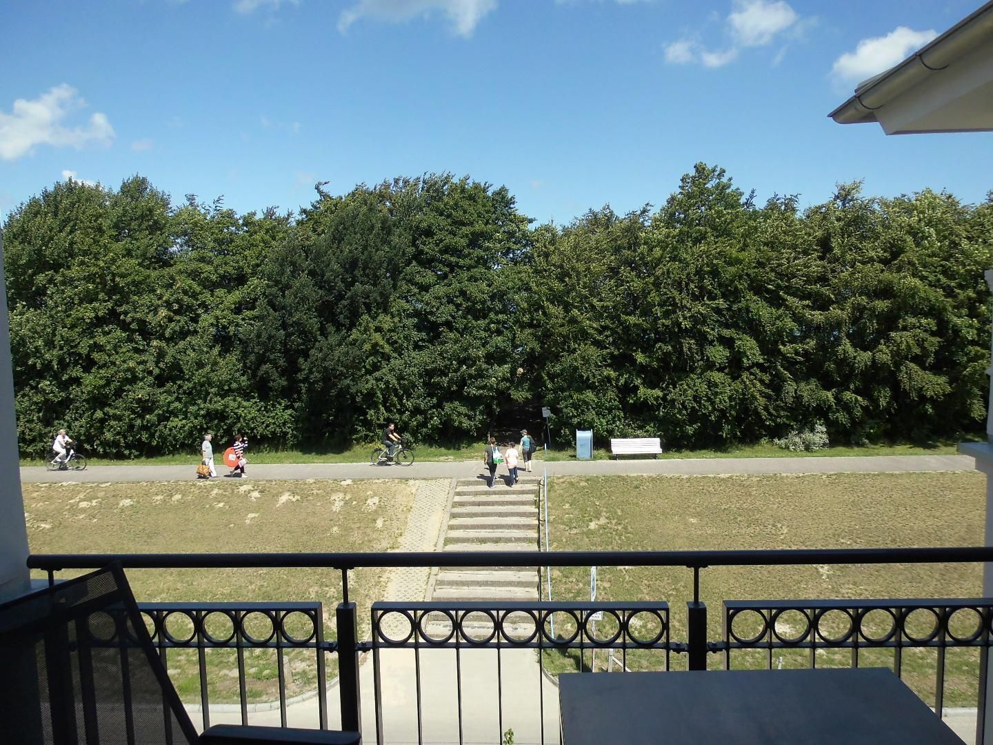 Un balcon donnant sur un parc, un sentier et un banc.