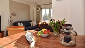 Un salon moderne avec une table à manger en bois, un canapé, un vase de fleurs et une bougie.