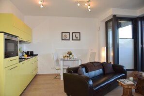 Ein kompakter Wohnbereich mit Küchenzeile, Essbereich und einer Sitzecke mit Sofa und Couchtisch.