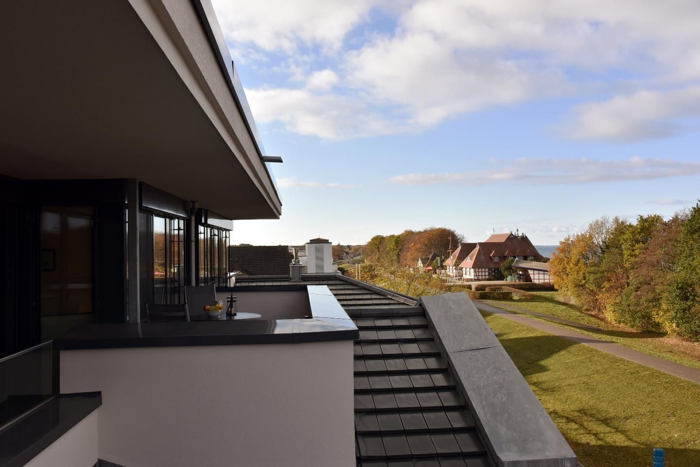 A modern building with a flat roof, large windows, and a view of a residential area with houses and trees.