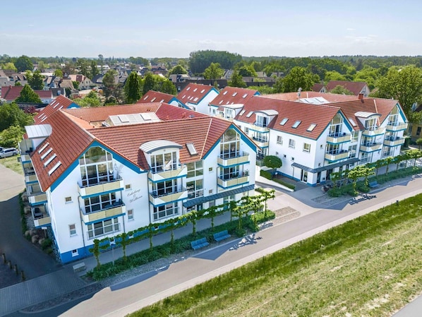 Un immeuble d’appartements moderne doté de nombreux balcons, de grandes fenêtres et d’un toit recouvert de tuiles rouges.