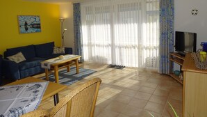 A living room with a sofa, coffee table, and television. - Comfortable vacation apartment in first beach row with balcony in Zingst - Residence (Zingst)