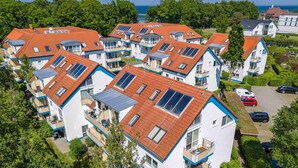 Ein Wohngebiet mit modernen Häusern, die Satteldächer und Solaranlagen haben.
