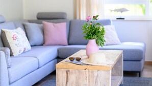 En stue med en grå sofa, et træ sofabord og en pink vase med blomster.
