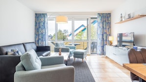 A modern living room with a sofa, armchairs, a coffee table, and a TV. - Comfortable vacation apartment Residenz am Strand 1-11 in the first row to the Baltic Sea - (Zingst)