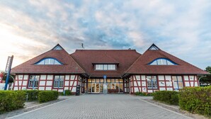 En traditionel bindingsværksbygning med en symmetrisk facade, en central indgang og en belagt sti hen til den.