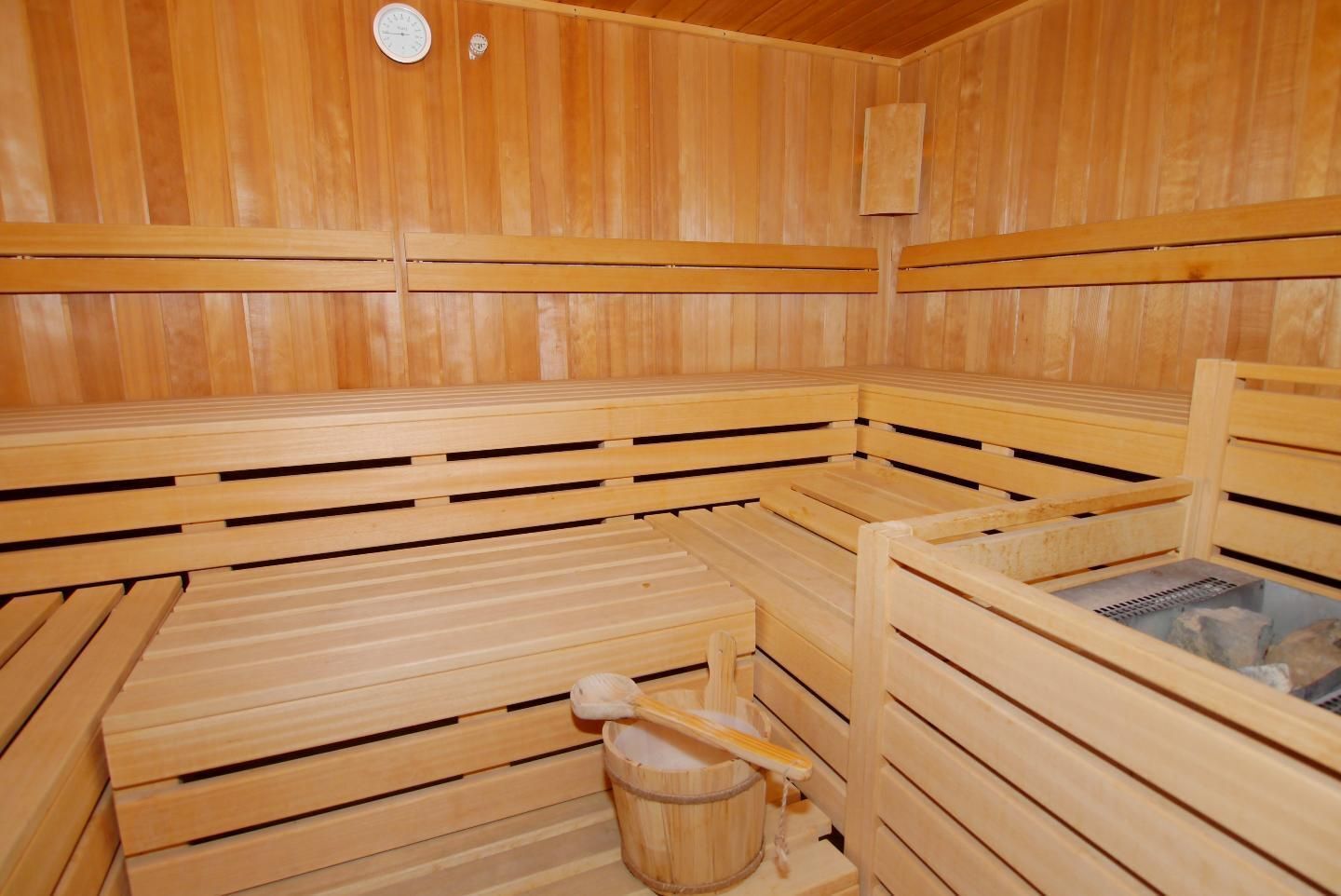 Eine Sauna mit Holzbänken, einem Eimer und einer Heizung.