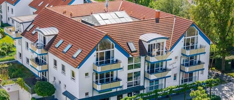 A multi-story hotel with a red-tiled roof, balconies, and a garden area.