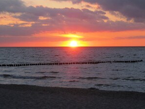 A sunset over the ocean with a breakwater in the foreground. - Comfortable vacation apartment in the first row to the Baltic Sea with balcony in Zingst - (Zingst)