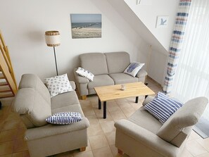 A living room with a sofa, armchairs, a coffee table, and a floor lamp. - Comfortable vacation apartment in the first row to the Baltic Sea with balcony in Zingst - (Zingst)