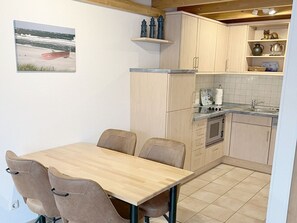 A compact kitchen with a dining table and chairs, a small oven, and a sink. - Comfortable vacation apartment in the first row to the Baltic Sea with balcony in Zingst - (Zingst)