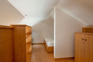 A small, well-lit room with wooden furniture, including a bed, a desk, and a wardrobe. - Comfortable vacation apartment in the first row to the Baltic Sea with balcony in Zingst - (Zingst)