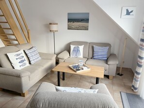 A modern living room with a sofa set, a coffee table, and a painting on the wall. - Comfortable vacation apartment in the first row to the Baltic Sea with balcony in Zingst - (Zingst)