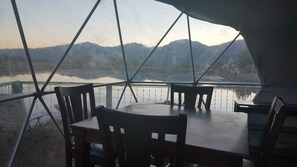 Comedor con una mesa y sillas, ventanas amplias con vistas a montañas y un lago.