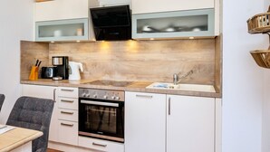 A compact kitchen with a built-in oven, a coffee maker, and a microwave. - Wohnung 2-28 - Residenz am Strand (Zingst)