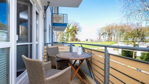 A balcony with wicker furniture and a table, overlooking a green landscape. - Wohnung 2-28 - Residenz am Strand (Zingst)
