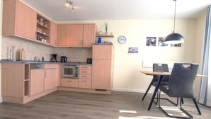 Une cuisine moderne avec des meubles en bois, un four encastré et un coin repas comprenant une table et des chaises.