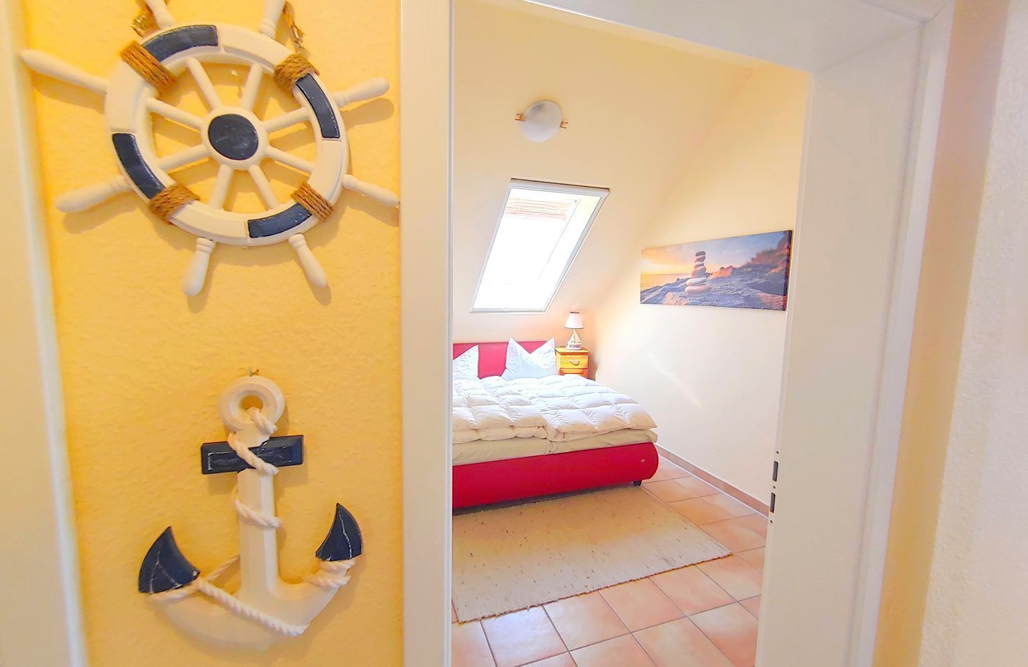 A bedroom with a bed, a nightstand, a lamp, and a painting on the wall.