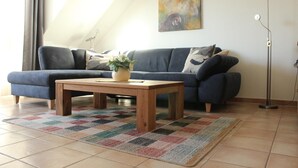 Una sala de estar con un sofá, una mesa de centro, una alfombra y un cuadro en la pared.