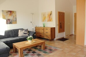 Ein Wohnzimmer mit einer Couch, einem Holztisch, einem Schrank und einer Tür.