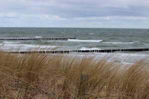 A beach with waves crashing against a wooden breakwater.