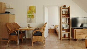 Una sala moderna con comedor, estantería, televisor y un cuadro.