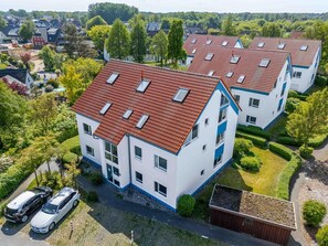 A residential building with a red-tiled roof, multiple windows, and a well-maintained garden. - Comfortable vacation apartment in direct beach location - Residence on the beach (Zingst)