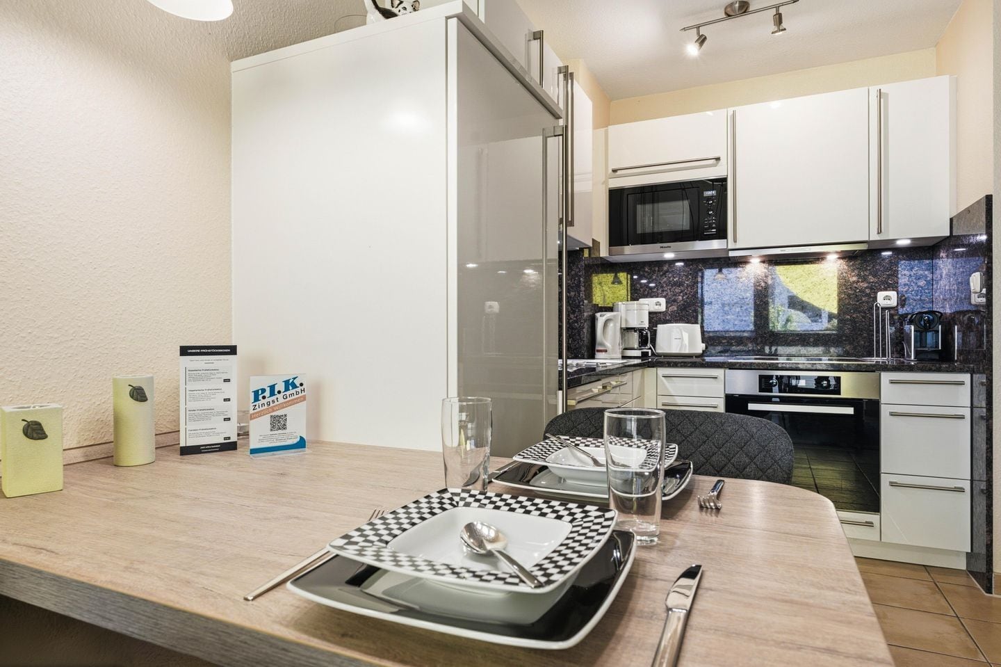 A modern kitchen with white cabinets, a microwave, and a coffee machine.