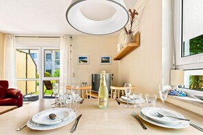 Un coin repas avec une table dressée pour deux personnes, une bouteille de champagne et un téléviseur en arrière-plan.