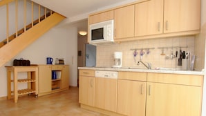 A compact kitchen with wooden cabinets, a microwave, and a coffee maker. - Comfortable vacation apartment in the first row on the beach of Zingst with balcony - (Zingst)