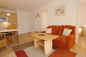 Un espacio habitable compacto con kitchenette, comedor y sofá.