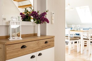 A modern kitchen with wooden cabinets, a white countertop, and a vase with purple flowers. - Modern apartment on the beachfront with balcony in Zingst - Residenz am (Zingst)