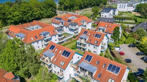 Zona residencial con varias casas de dos pisos, techos de tejas rojas y paneles solares.