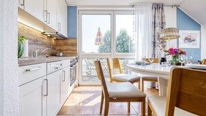 Una cocina moderna con armarios blancos, encimera de madera y un comedor con mesa y sillas.