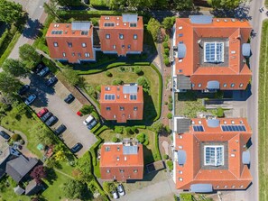 Ein Wohngebiet mit mehreren Gebäuden mit roten Dächern, jedes davon mit Solaranlage.