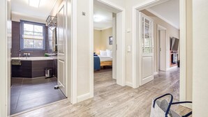 Ein modernes Interieur mit Bad, Schlafzimmer und Wohnbereich, mit Holzdielenböden und weißen Wänden.
