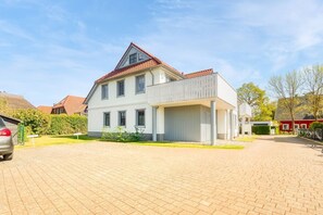 Une maison à deux étages avec un balcon, un garage et une allée pavée.
