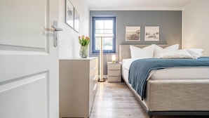 Ein Schlafzimmer mit Bett, Nachttischen, einer Stehlampe und Bildern an der Wand.
