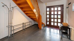 A staircase with wooden steps and a metal railing, leading to a door with multiple windows.