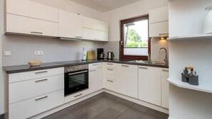 A modern kitchen with white cabinetry, a black oven, and a window providing natural light.