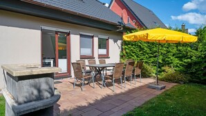 An outdoor patio with a table and chairs, a yellow umbrella, and a stone planter.