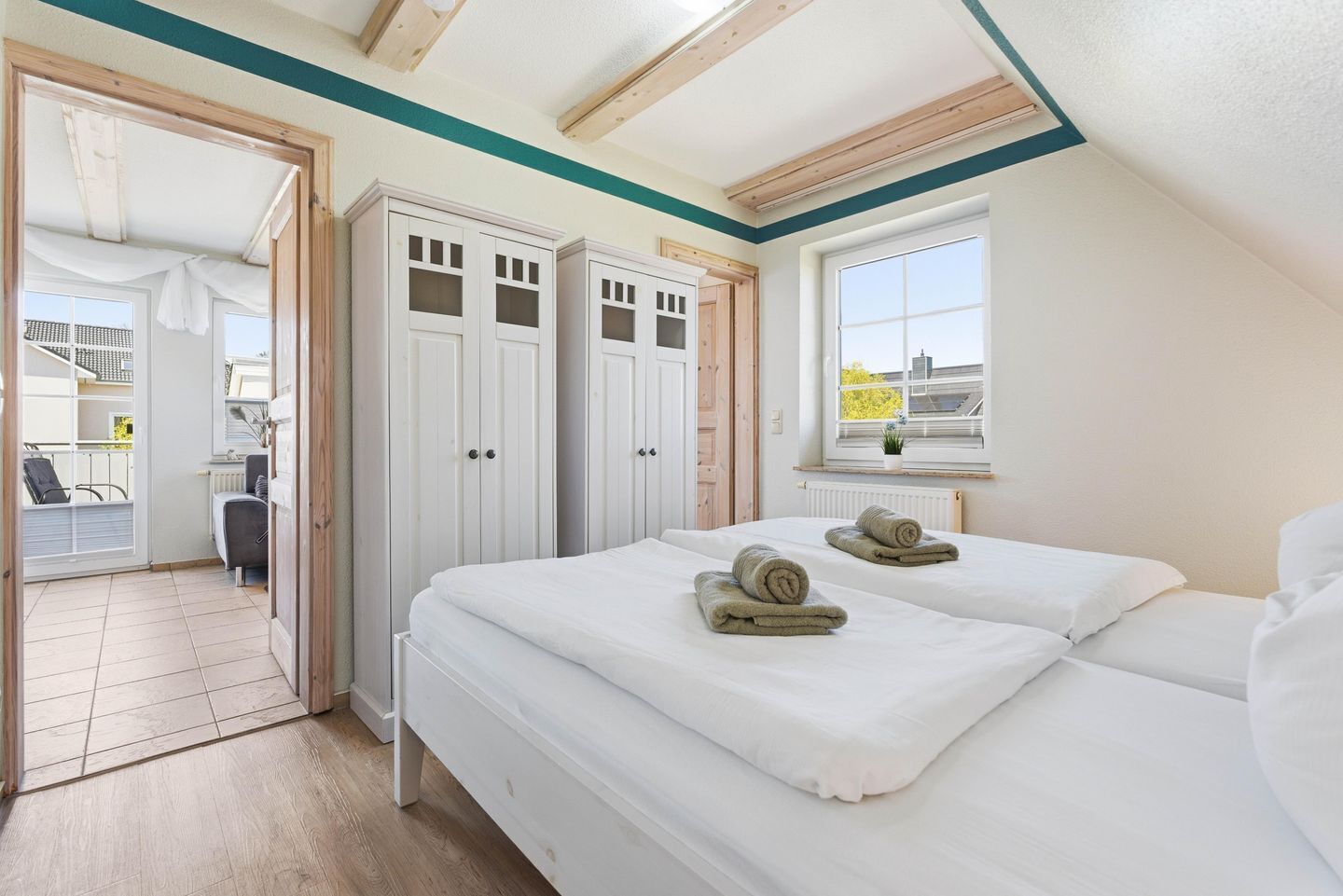 A bedroom with two beds, a window, and a view of the outside.