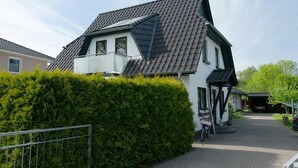 Une maison à deux étages, dotée d’un toit à forte pente, d’un garage bien visible et d’un vélo garé à l’extérieur.